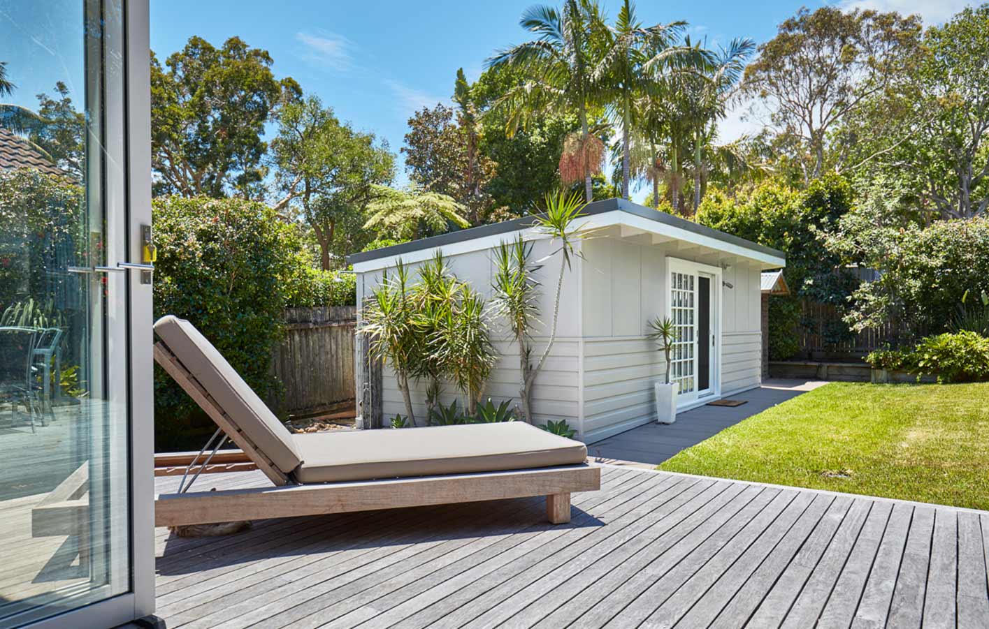 Überdachter Bereich eines Gartenhauses aus Holz, mit Tisch und Stühlen dekoriert.