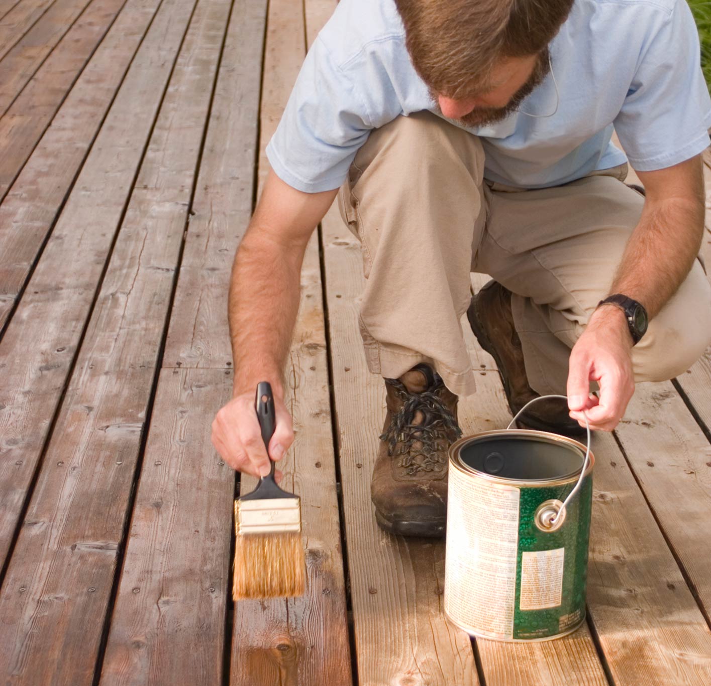 Verschiedene Holzlasuren und ein Pinsel, bereit zur Anwendung auf Holzoberflächen im Außenbereich.