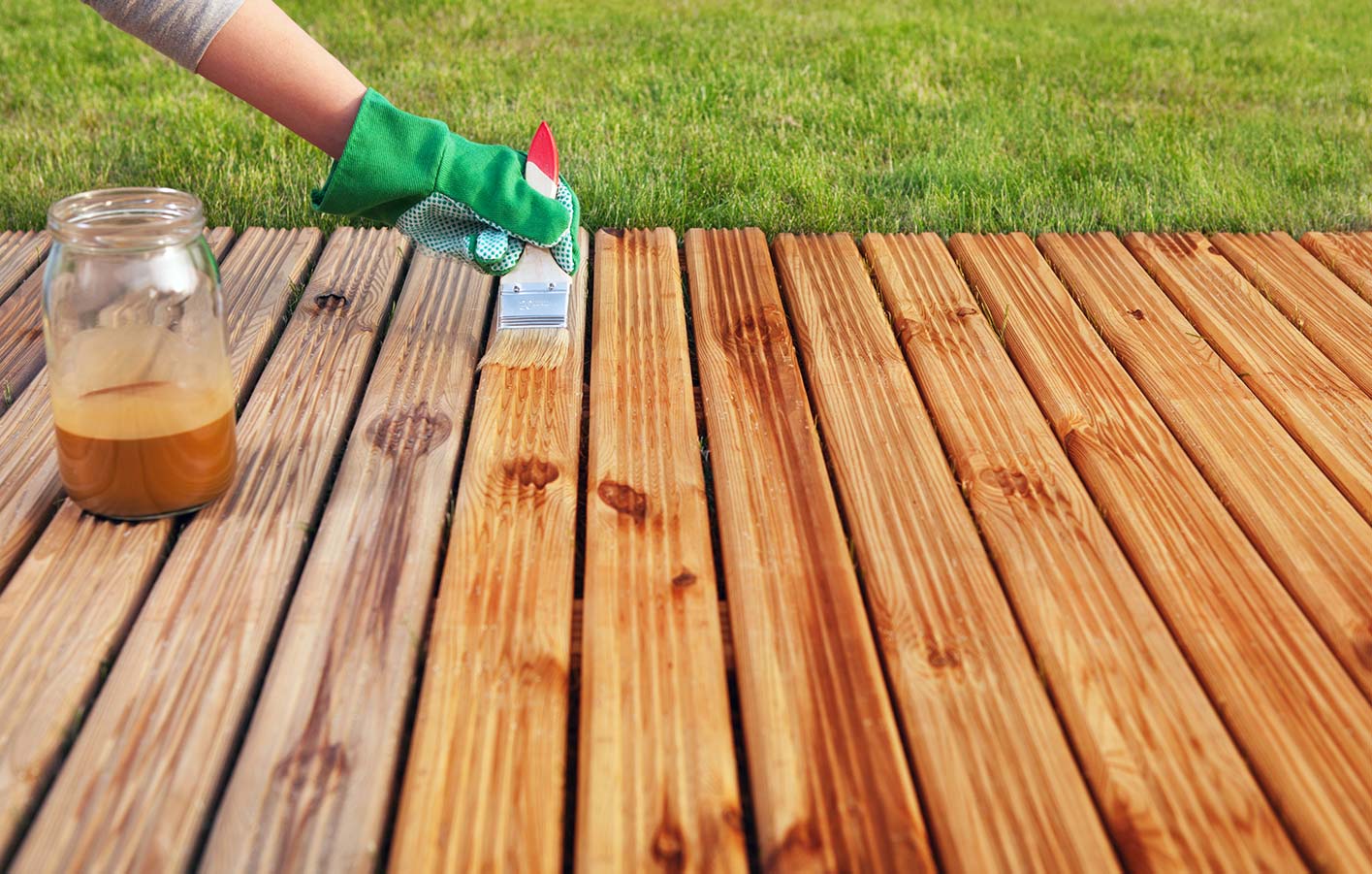 Holzterrasse wird mit einem Pinsel behandelt